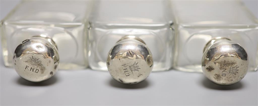 A set of three George V silver topped glass toilet jars, London, 1912, 13.2cm, with engraved initial.